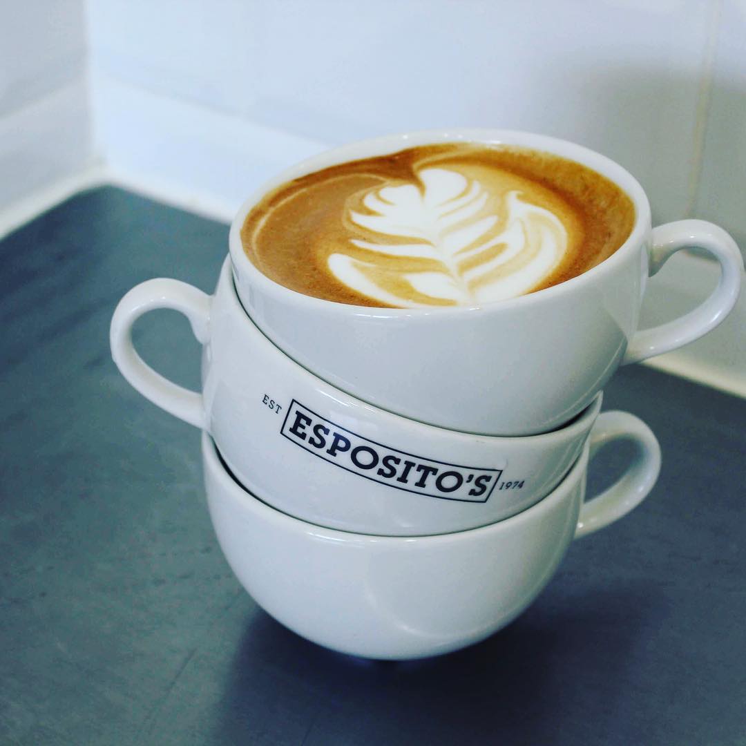 Stack of branded Esposito’s takeaway coffee cups on counter.
