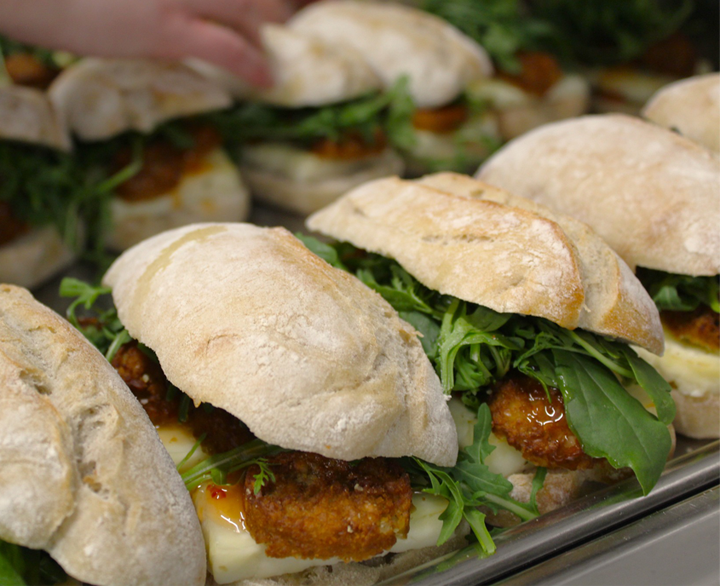 Freshly prepared ciabatta sandwiches filled with crispy chicken and greens, ideal for corporate catering events.