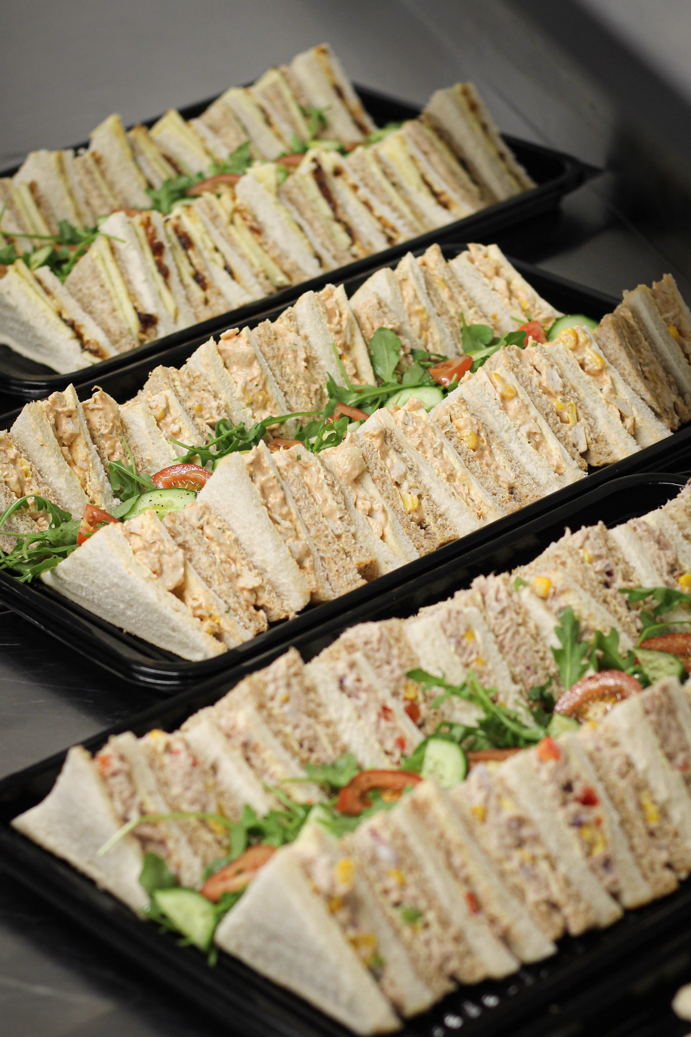 Variety of freshly prepared sandwich platters filled with crisp vegetables and chicken slices, perfect for corporate catering.
