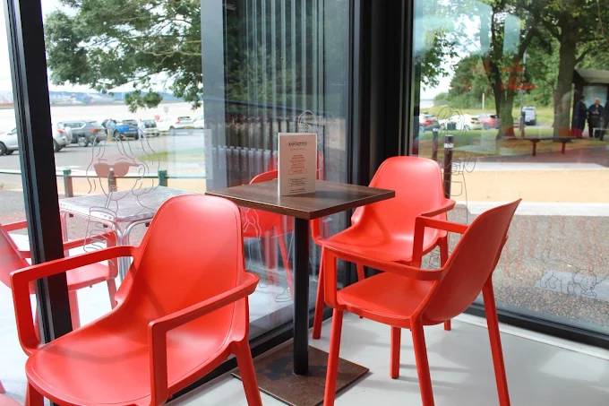 Indoor seating area at Esposito's Pickering's Pasture with red chairs and riverside views